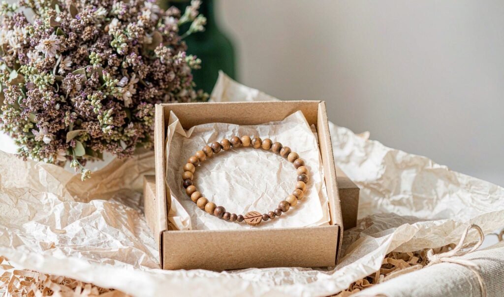 A wooden bead bracelet in a kraft gift box with dried flowers
